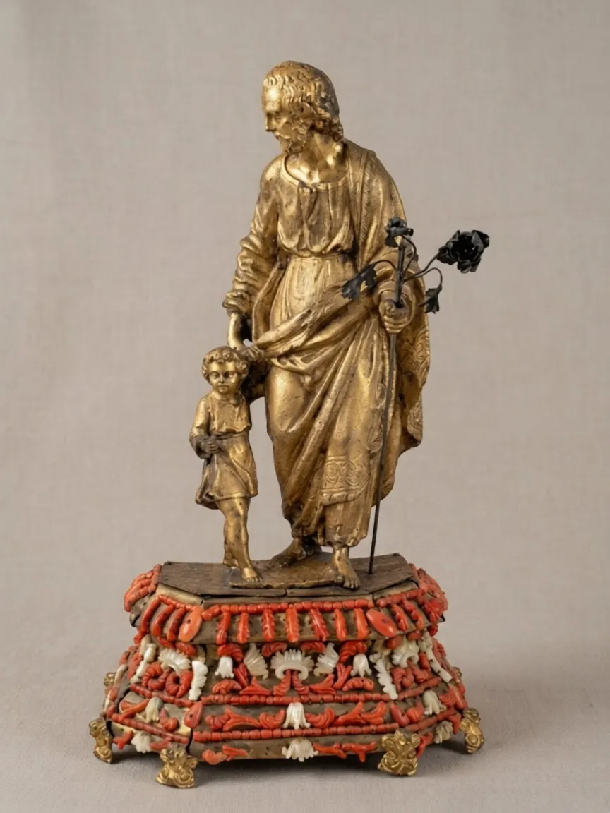Escultura de santo em madeira dourada sobre base decorada com coral vermelho e madrepérola