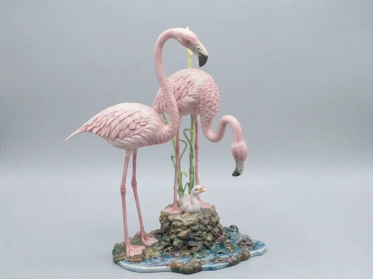 Grupo escultórico em porcelana representando dois flamingos e uma cria sobre um ninho